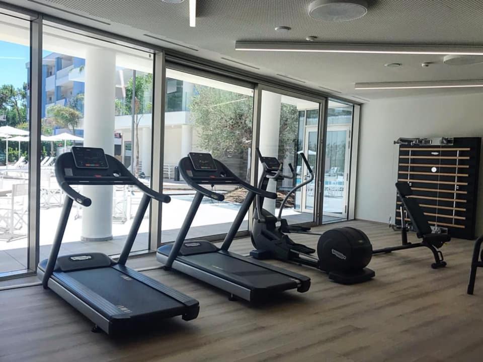 - une salle de sport avec plusieurs tapis de course dans une pièce dotée de fenêtres dans l'établissement YOUMAMI Suite Hotel Wellness&Spa, à Giulianova