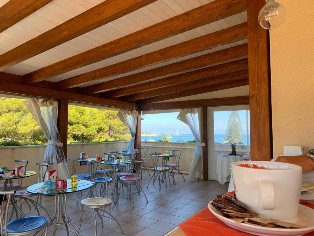 une pièce avec des tables, des chaises et des fenêtres dans l'établissement Hotel Iride by Marino Tourist, à San Vito Lo Capo