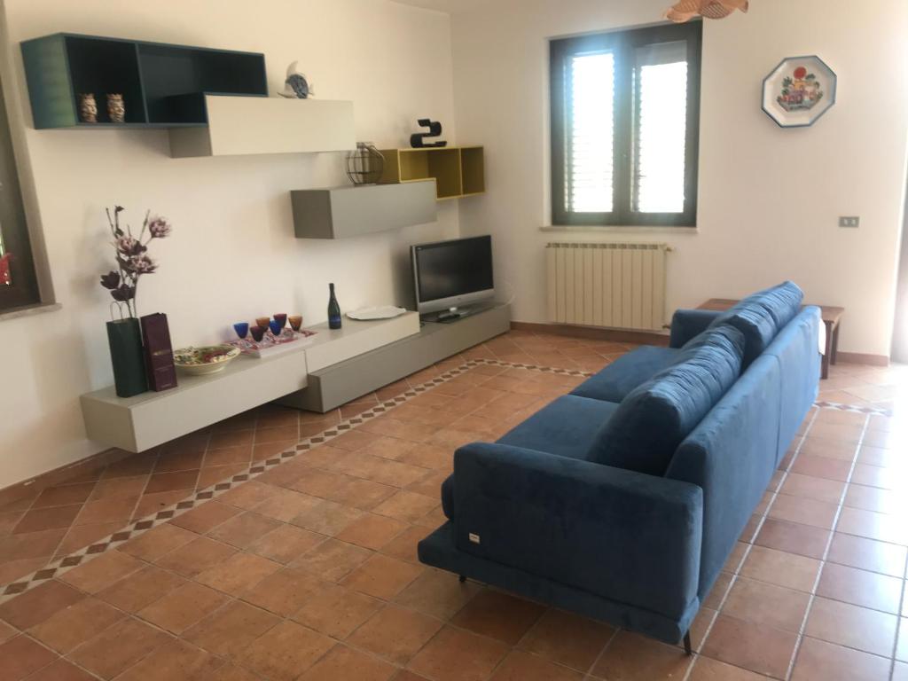 un salon avec un canapé bleu et une télévision dans l'établissement ALBA SULLO STRETTO, à Messina