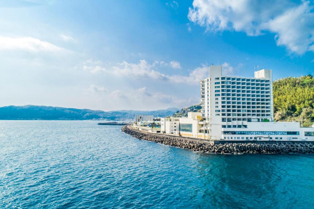 un grand bâtiment au bord d'un plan d'eau dans l'établissement Hotel Sun Hatoya, à Itō