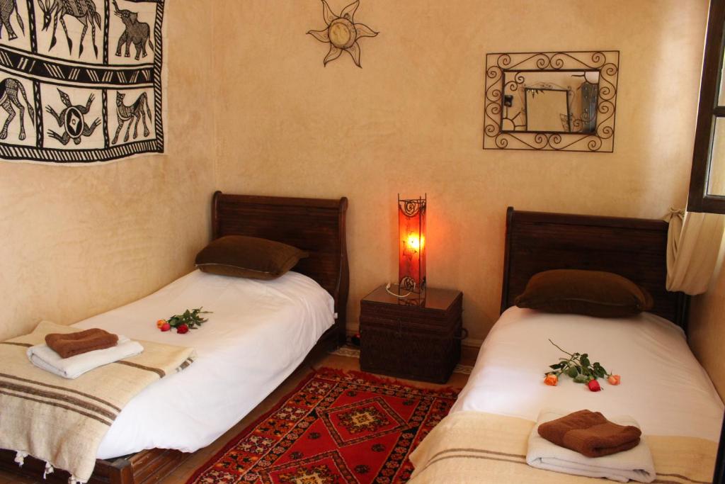 deux lits dans une chambre avec un miroir dans l'établissement Riad Salmiya Dune, à Essaouira