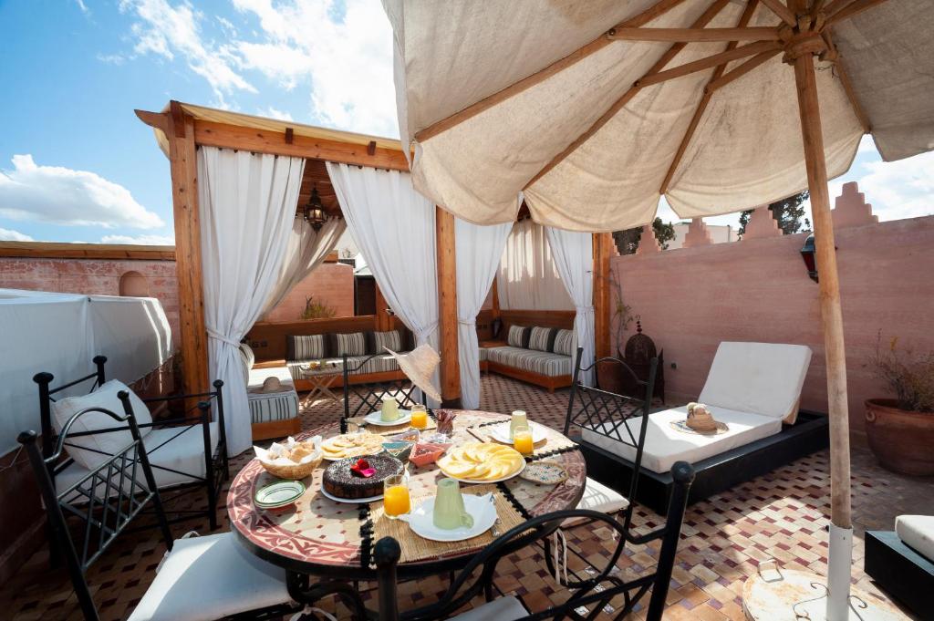 une table et des chaises avec un parasol sur une terrasse dans l'établissement Riad des trois palais, à Marrakech 26 autres photos