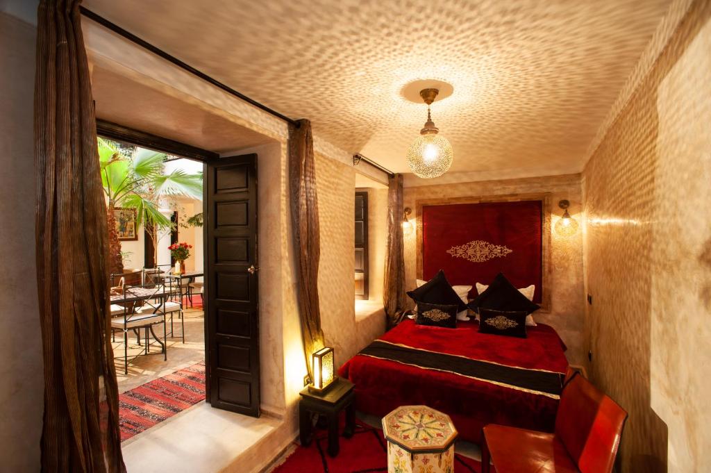 - une chambre avec un lit rouge et un balcon dans l'établissement Riad des trois palais, à Marrakech