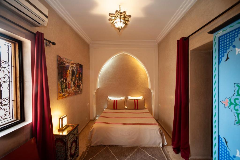 - une chambre avec un lit dans une pièce dotée de rideaux rouges dans l'établissement Riad des trois palais, à Marrakech