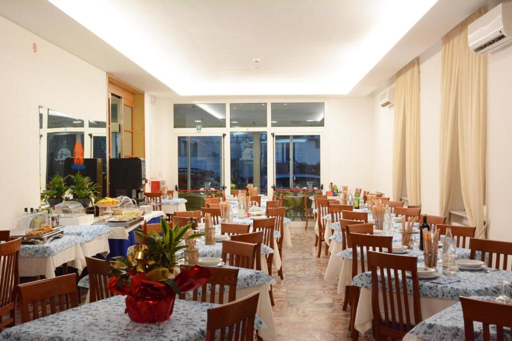 une salle à manger avec tables et chaises et une pièce avec fenêtres dans l'établissement Dea Della Salute Hotel, à Bellaria-Igea Marina