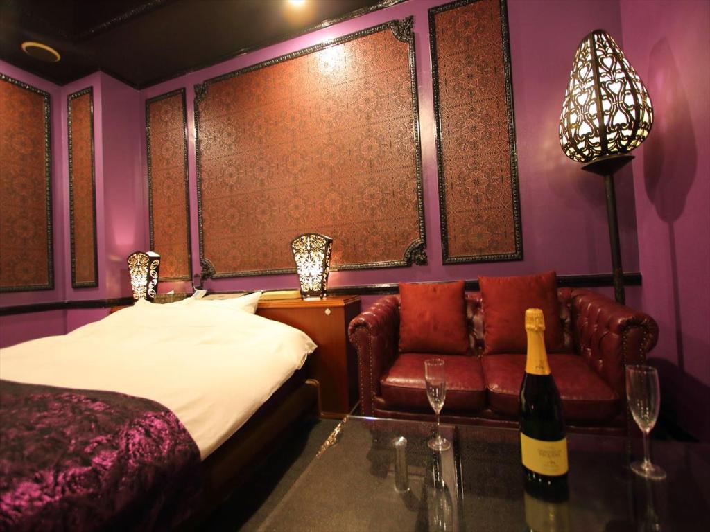 une chambre avec un lit, un canapé et une bouteille de vin dans l'établissement Hotel GIG (Adult Only), à Kawagoe