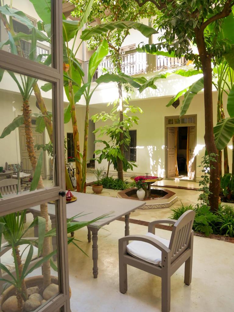 un patio avec une table, des chaises et des arbres dans l'établissement Riad Dar Aman, à Marrakech