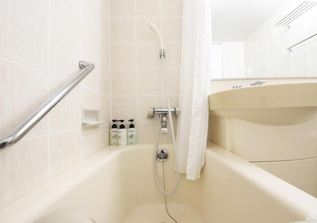 La salle de bains blanche est pourvue d'une douche et d'une baignoire. dans l'établissement Kyukamura Ura-Bandai, à Kitashiobara