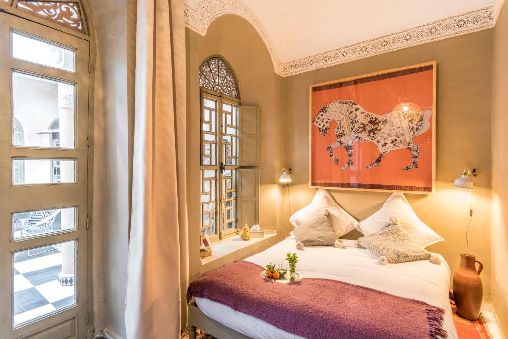 - une chambre avec un lit et une peinture de cheval dans l'établissement Riad Hissan, à Marrakech