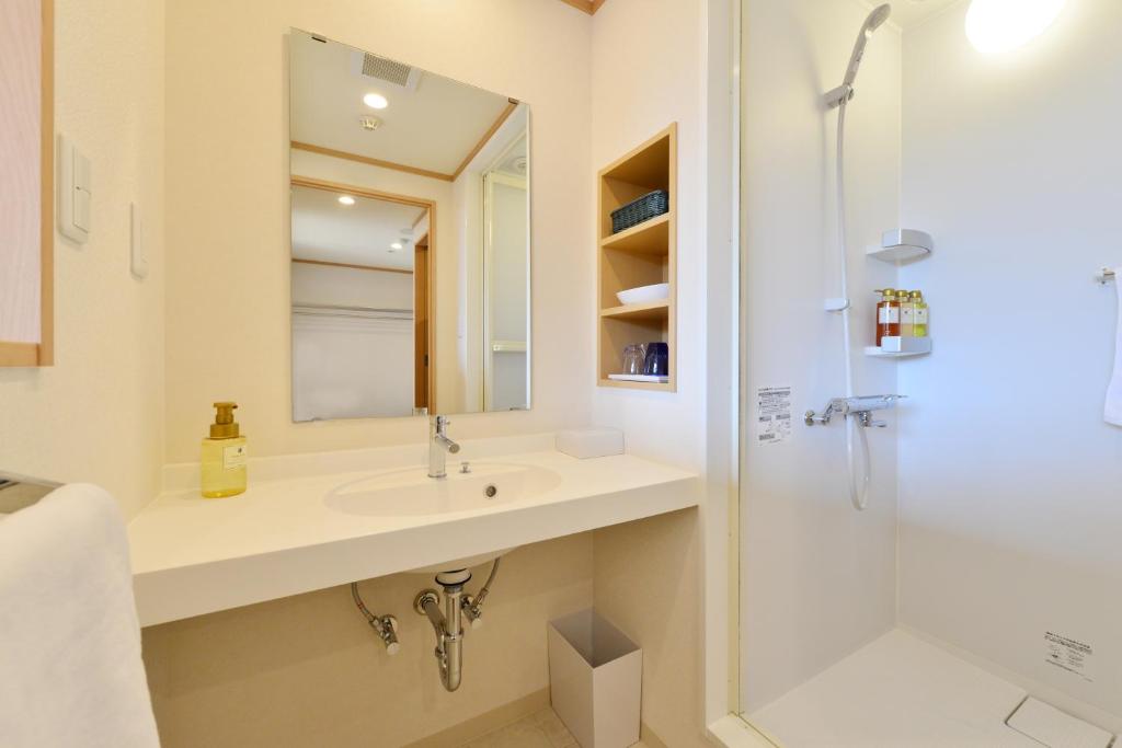 une salle de bain avec un lavabo et une douche dans l'établissement Washu Blue Resort風籠 Kasago, à Kurashiki