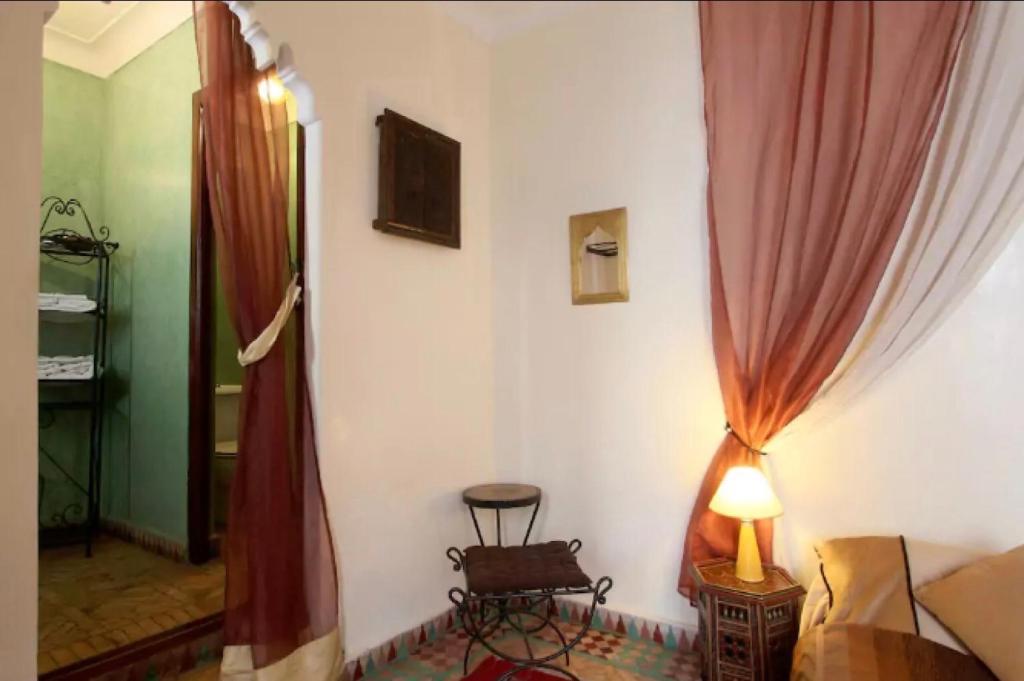 - une chambre avec des rideaux rouges, une chaise et une lampe dans l'établissement Riad Al Warda, à Marrakech