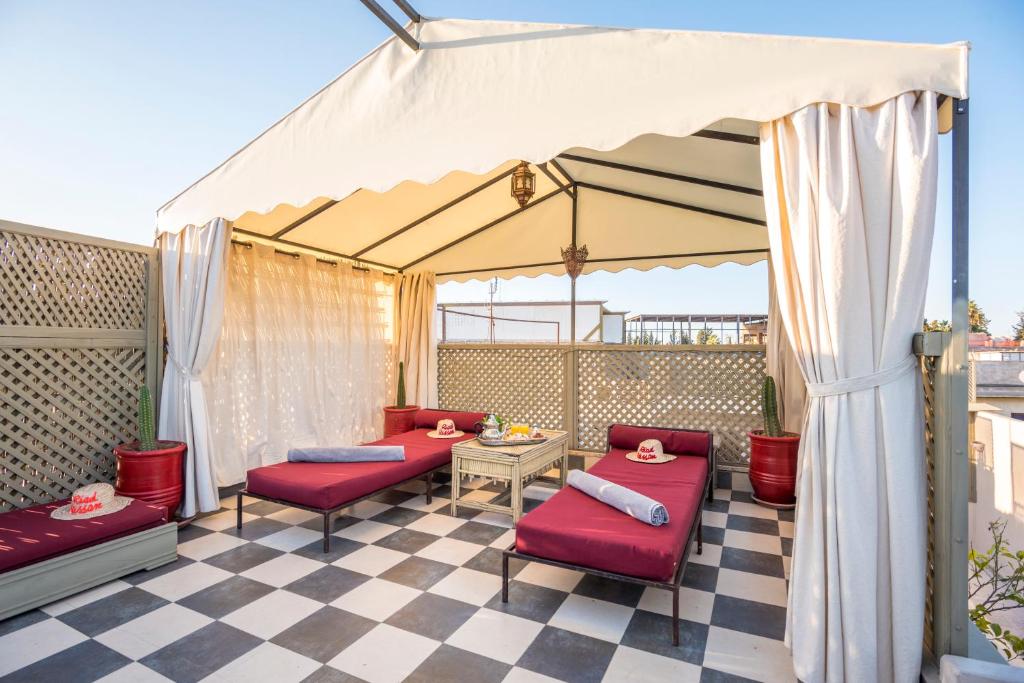 d'une terrasse avec des chaises rouges et un auvent blanc. dans l'établissement Riad Hissan, à Marrakech