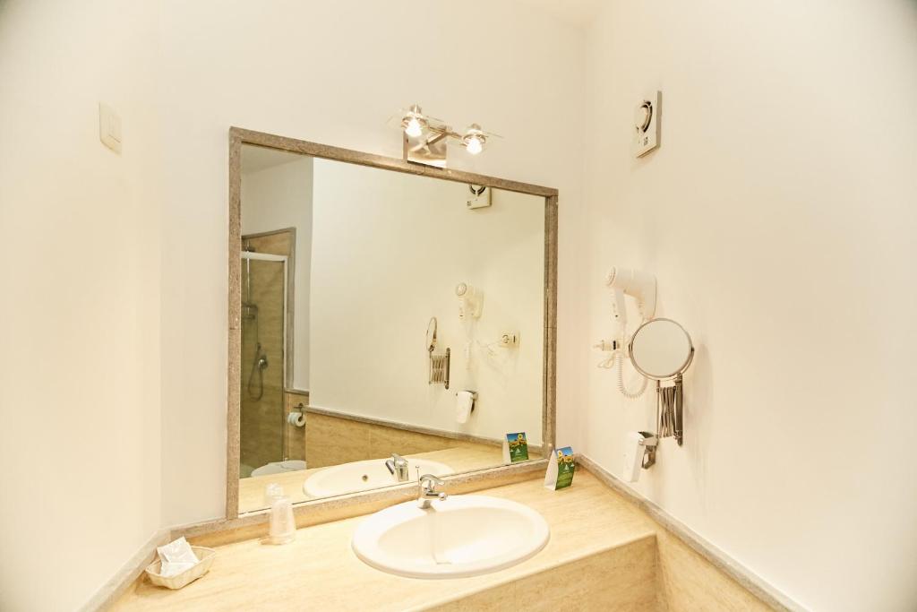 une salle de bain avec un lavabo et un grand miroir dans l'établissement Hotel Enterprise, à Montalto di Castro