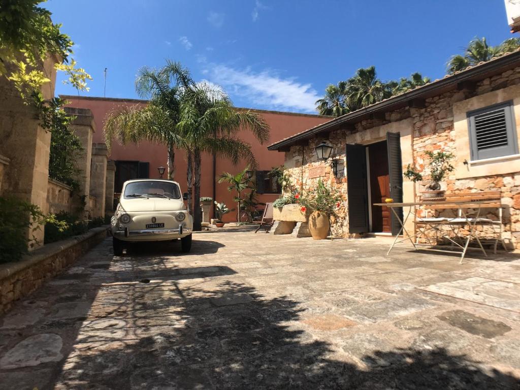 une voiture blanche garée dans une cour à côté d'un immeuble dans l'établissement VILLA EVA, à Castrignano del Capo