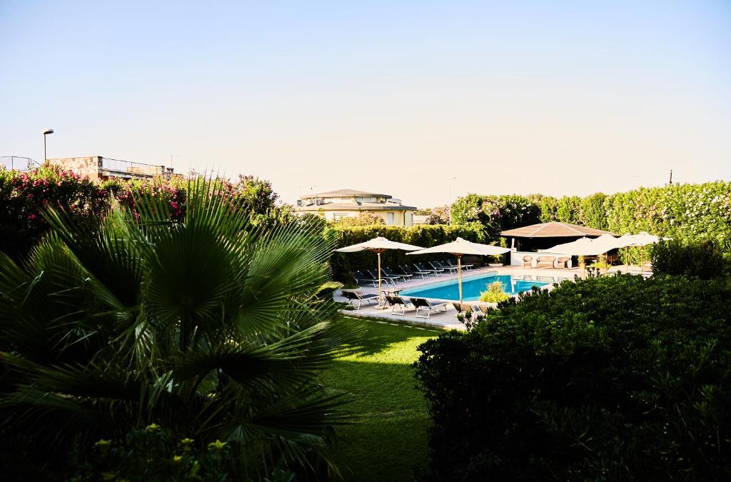 un complexe avec une piscine et des parasols dans l'établissement Hotel Enterprise, à Montalto di Castro