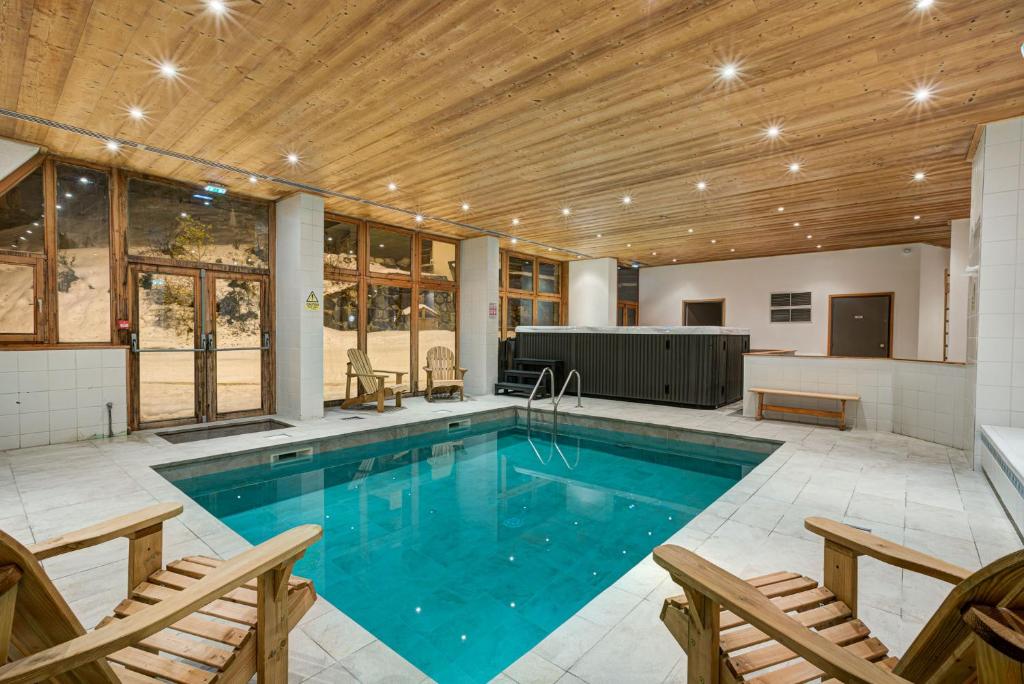 - une piscine dans une maison dotée d'un plafond en bois dans l'établissement Hôtel Le Montana, à La Tania