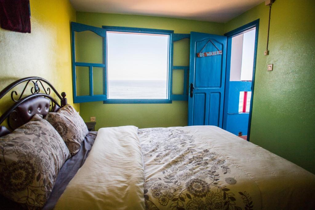 - une chambre avec un lit doté d'une porte bleue et d'une fenêtre dans l'établissement Auberge Maison Diyani, à Sidi Ifni