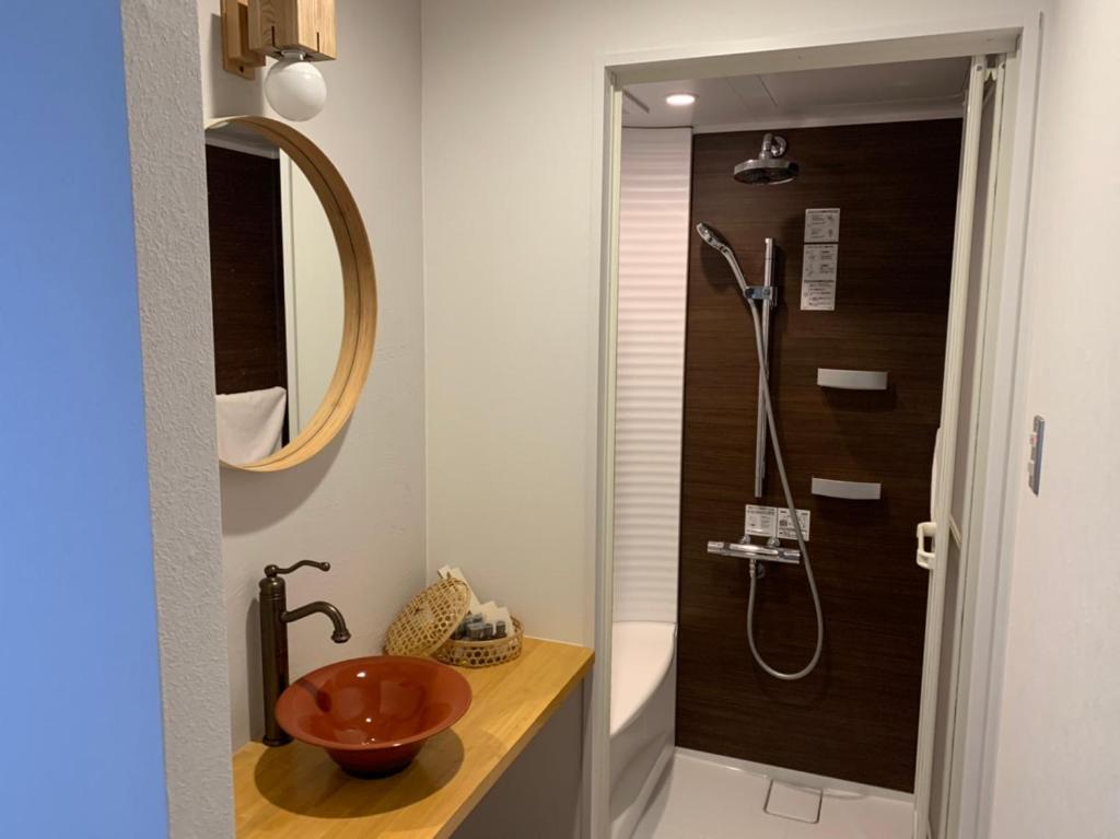 une salle de bain avec un lavabo et une douche dans l'établissement Miyajima Shiro, à Miyajima