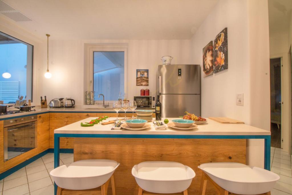 Il comprend une cuisine équipée d'un comptoir avec des chaises et d'un réfrigérateur. dans l'établissement TD Villa Levante Modern Luxury Villa with Sea View, à Monopoli