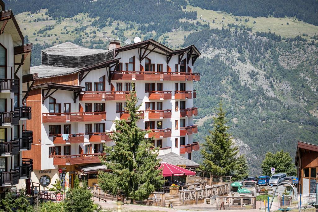 un grand bâtiment avec des arbres devant une montagne dans l'établissement Résidence Pierre & Vacances Le Britania, à La Tania