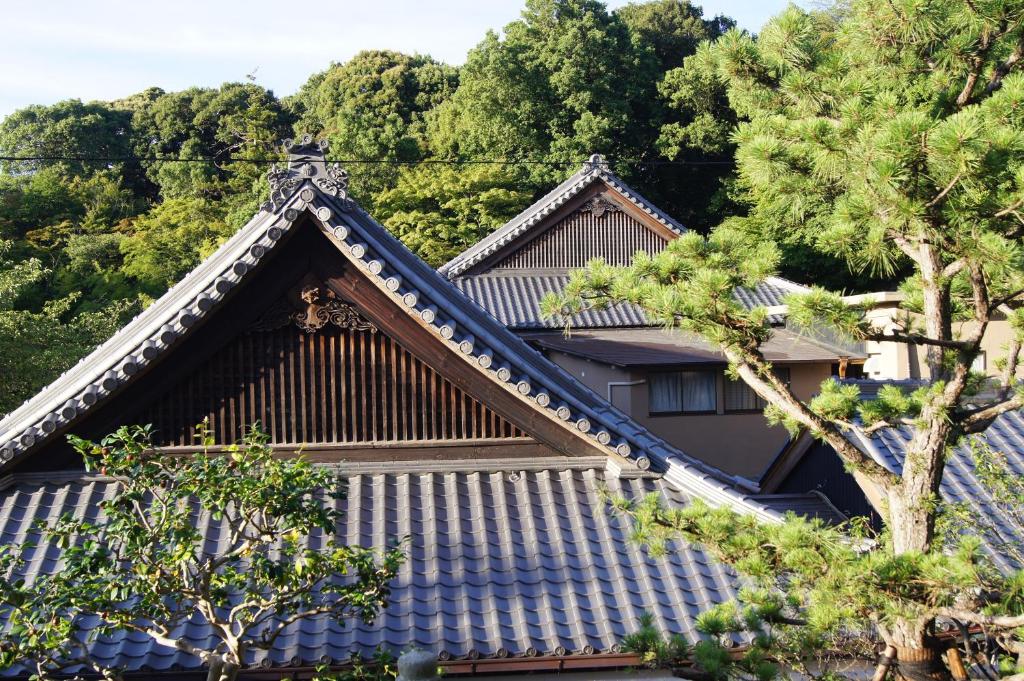 un toit d'un bâtiment avec des arbres en arrière-plan dans l'établissement Gyokuzoin, à Heguri