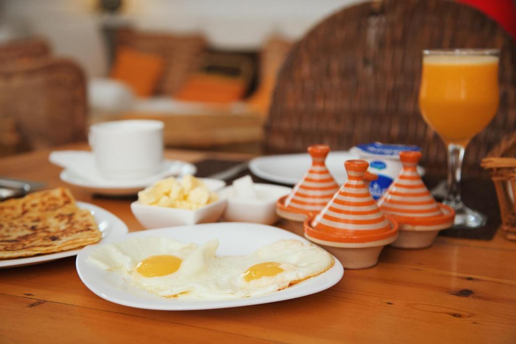 une table avec deux œufs sur une plaque et un verre de jus d'orange dans l'établissement Dar Liouba Hotel, à Essaouira