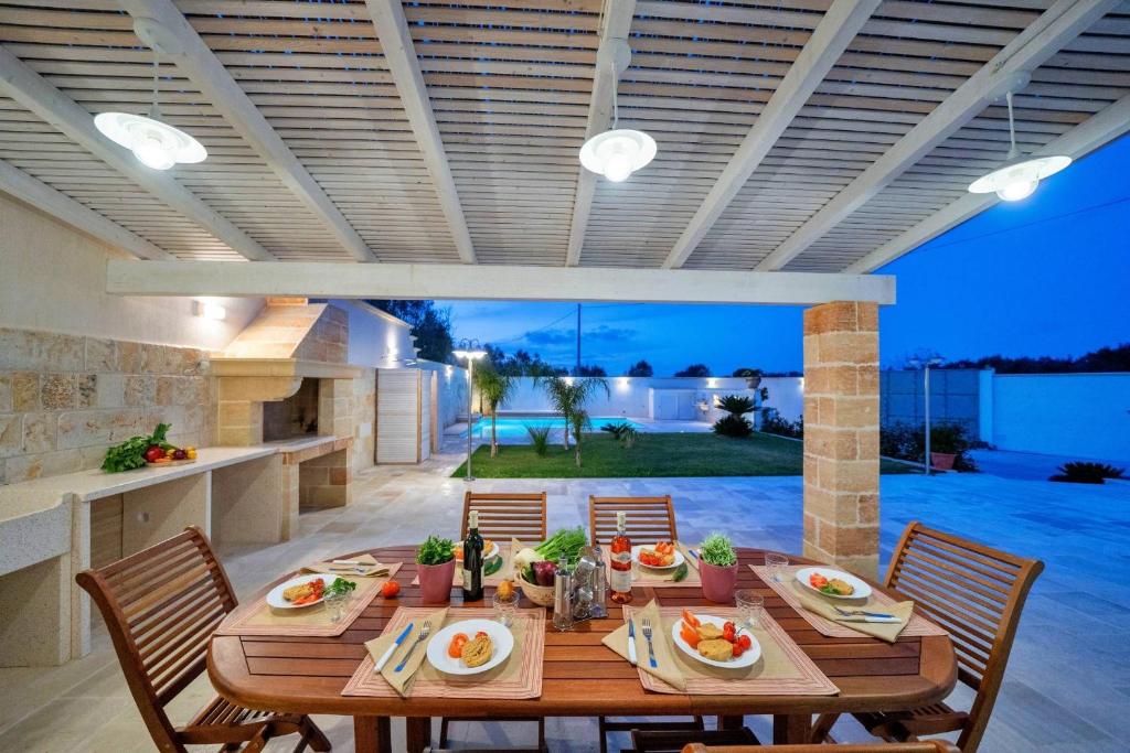 une salle à manger avec une table et des chaises ainsi qu'une terrasse dans l'établissement Villa Gargasole con Piscina privata nel Salento, à Alessano