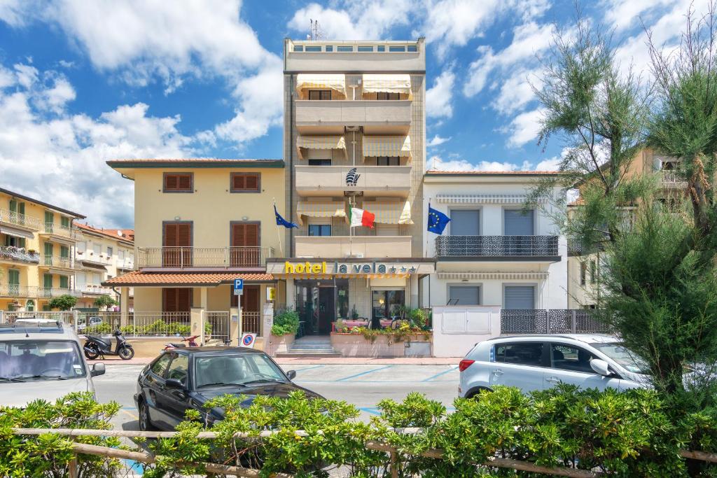 un bâtiment avec des voitures garées dans un parking dans l'établissement Hotel La Vela, à Lido di Camaiore