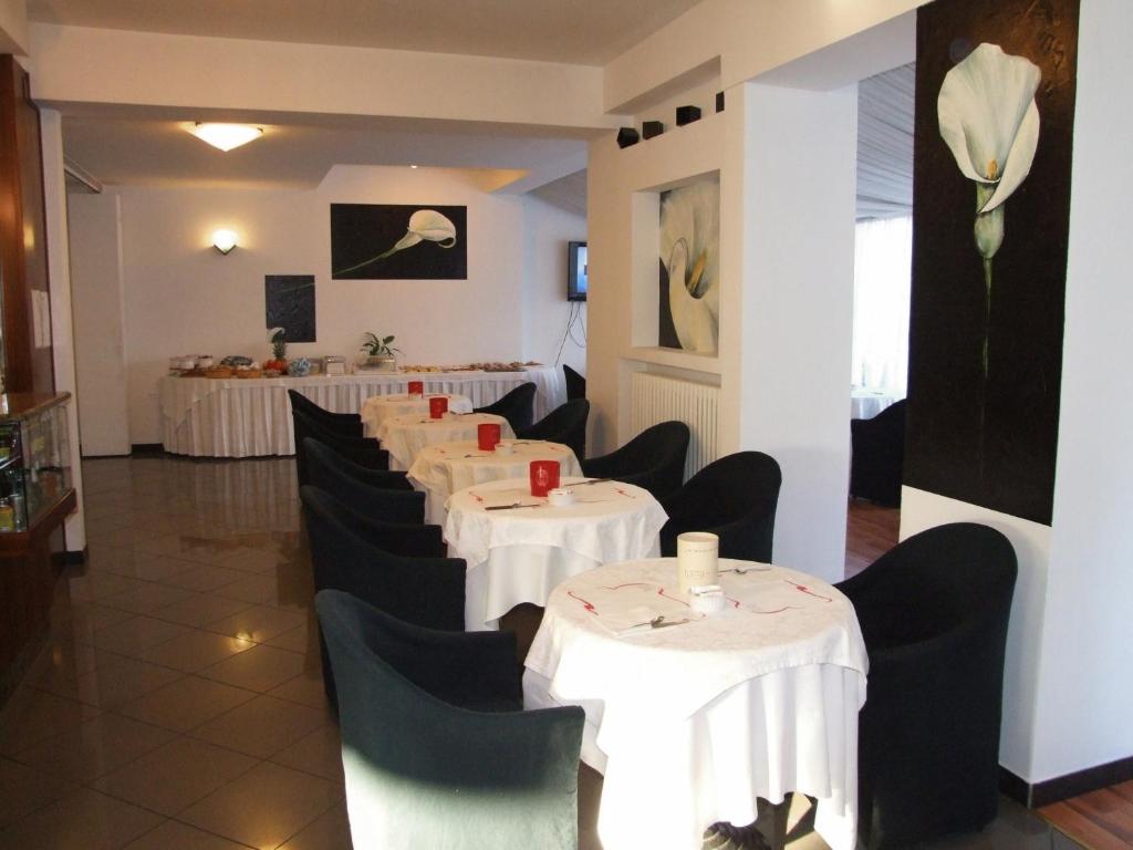 une salle à manger avec des tables blanches et des chaises noires dans l'établissement Hotel Mediterraneo, à Pesaro