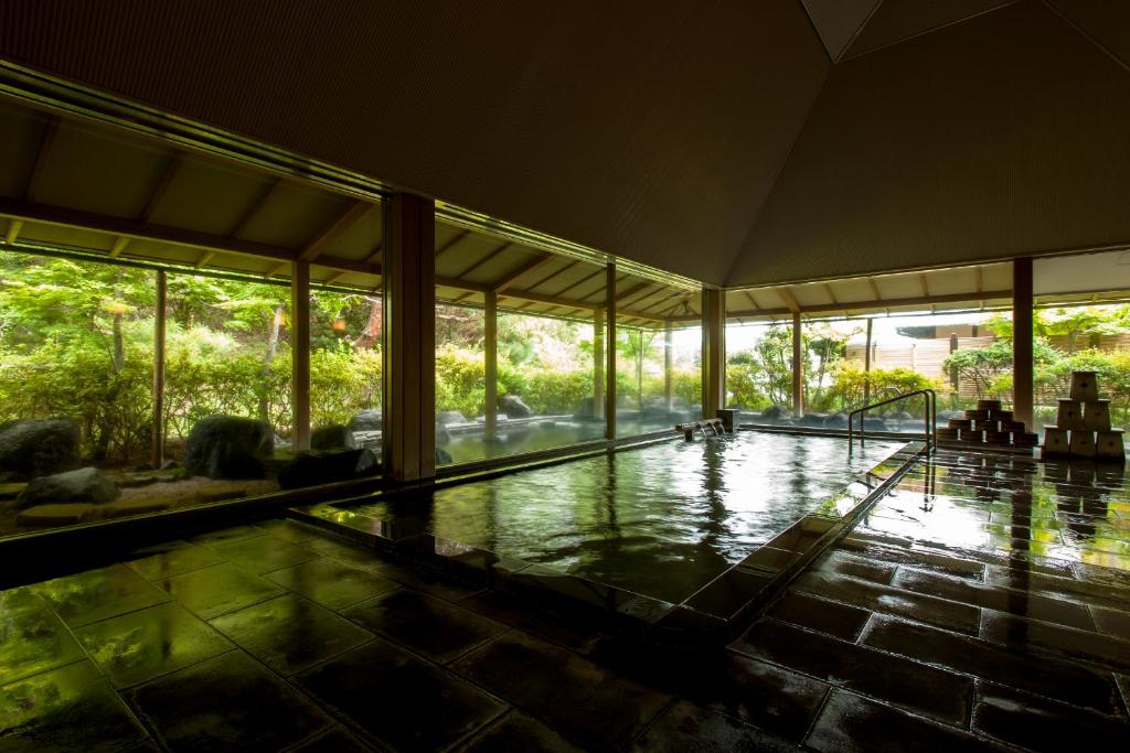 une piscine intérieure dans une maison avec des fenêtres dans l'établissement Sanyo-so, à Izunokuni