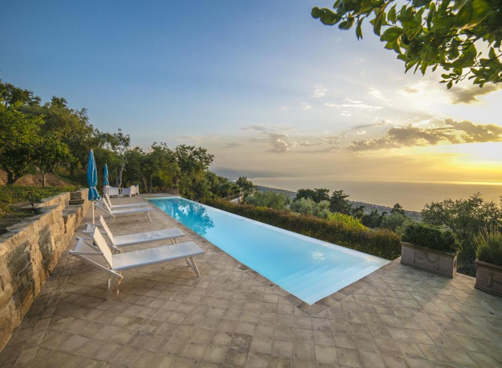 une piscine avec deux chaises longues et un parasol dans l'établissement Villa Laura, à Capo dʼOrlando