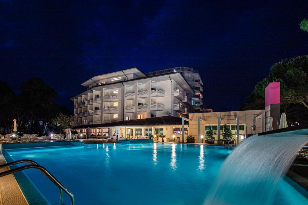 une piscine devant un immeuble la nuit dans l'établissement Hotel Bristol, à Lignano Sabbiadoro