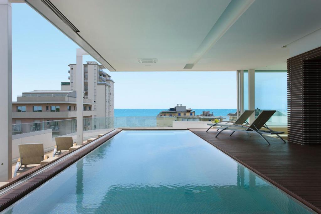 une piscine avec des chaises et une vue sur l'océan dans l'établissement Il Teatro, à Lido di Jesolo