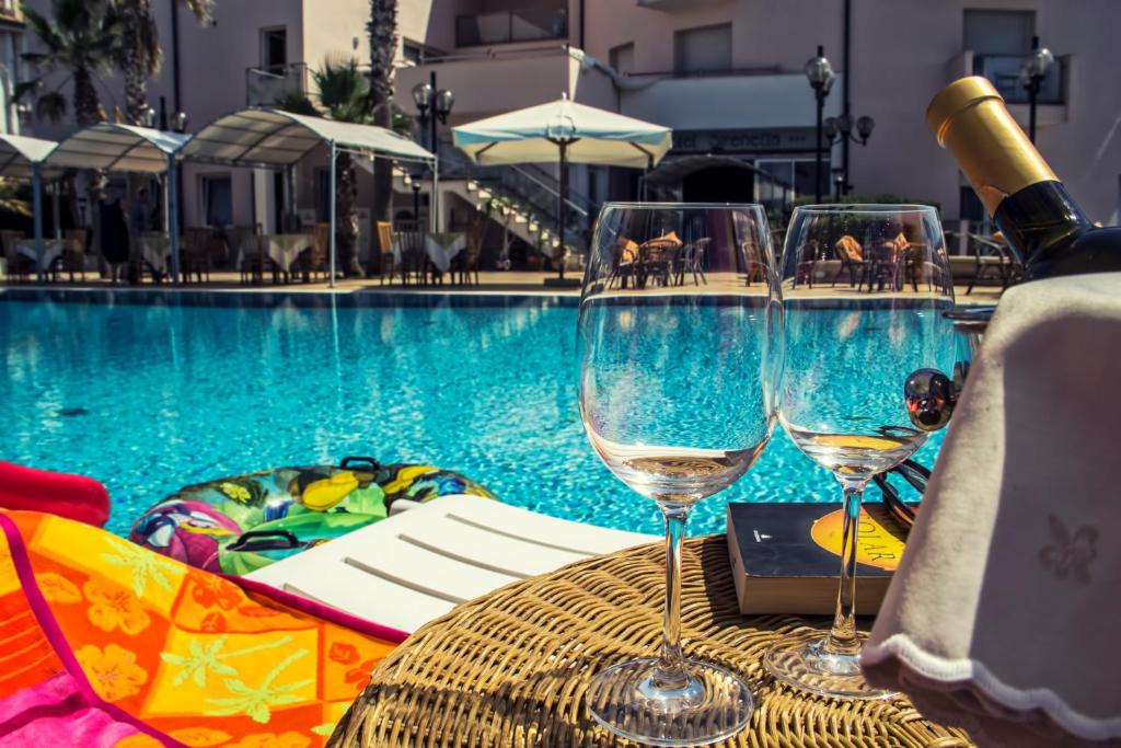 - une table avec des verres à vin à côté de la piscine dans l'établissement Hotel Sirenetta, à Isola delle Femmine
