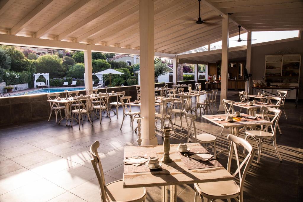 un restaurant avec des tables et des chaises et une piscine dans l'établissement Albaruja Hotel, à Costa Rei