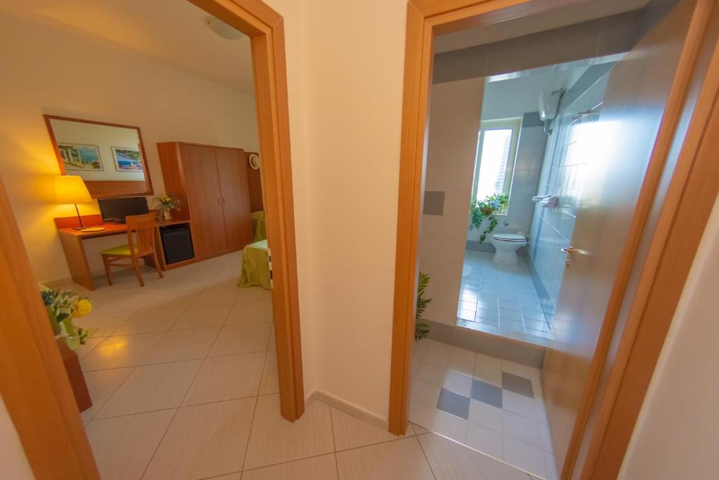 - un couloir avec une porte en verre menant à une salle de bains dans l'établissement Hotel Solaria, à Rodi Garganico