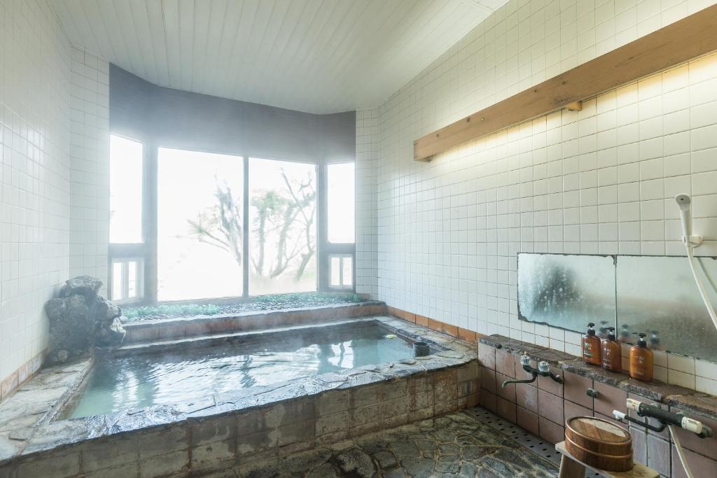 La salle de bains est pourvue d'une grande baignoire et d'une fenêtre. dans l'établissement Chojuyu Hakone, à Hakone
