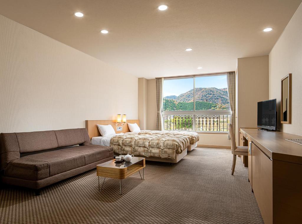 un salon avec un canapé, un lit et une télévision dans l'établissement The Gran Resort Kinosaki, à Toyooka