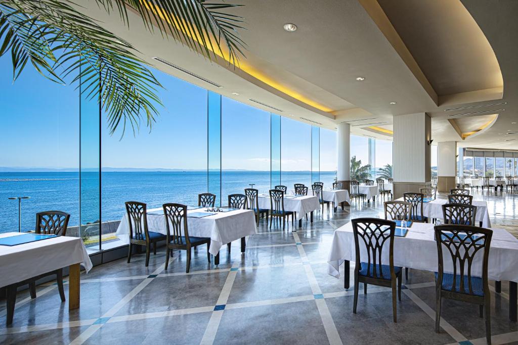 un restaurant avec des tables et des chaises et une vue sur l'océan dans l'établissement The Gran Resort Elegante Awajishima, à Awaji