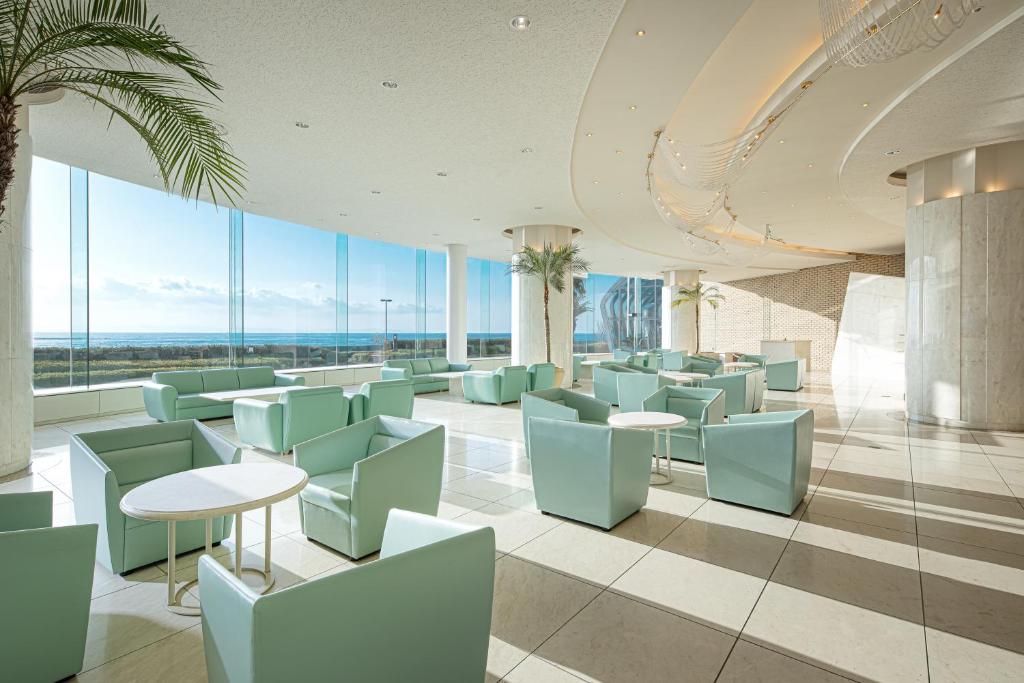 un restaurant avec des tables et des chaises bleues et de grandes fenêtres dans l'établissement The Gran Resort Elegante Awajishima, à Awaji