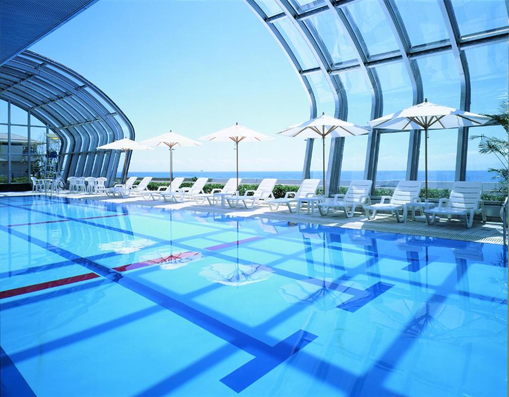 une piscine avec des chaises blanches et des parasols dans l'établissement The Gran Resort Elegante Awajishima, à Awaji