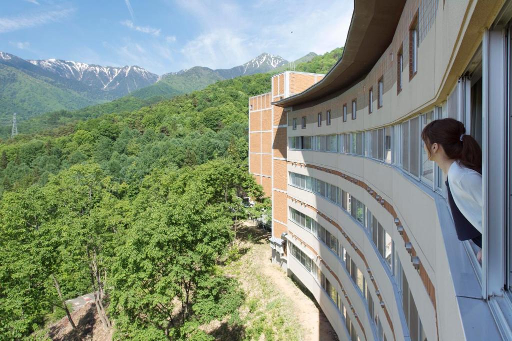 Une femme qui regarde les montagnes par une fenêtre dans l'établissement Izumigo AMBIENT Azumino Hotel, à Azumino