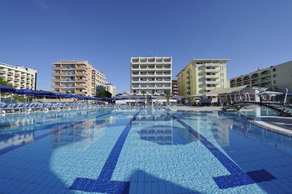 une grande piscine avec des bâtiments en arrière-plan dans l'établissement Hotel Lido Bibione Beach, à Bibione