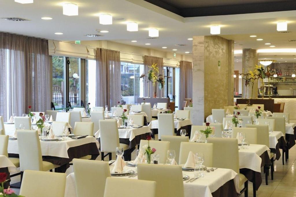 une salle à manger avec des tables blanches et des chaises blanches dans l'établissement Hotel Lido Bibione Beach, à Bibione