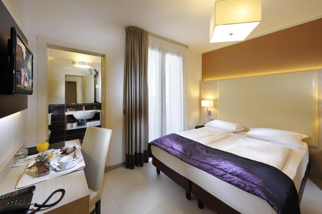 une chambre d'hôtel avec un lit, un bureau et un miroir dans l'établissement Hotel Lido Bibione Beach, à Bibione 38 autres photos