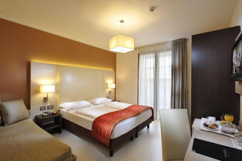 une chambre d'hôtel avec un lit et un canapé dans l'établissement Hotel Lido Bibione Beach, à Bibione