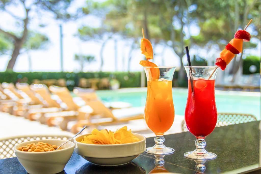 une table avec deux boissons et des bols de nourriture dessus dans l'établissement Hotel American, à Lignano Sabbiadoro