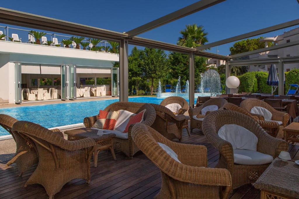 une terrasse avec des chaises en osier et une piscine dans l'établissement SeaPark SPA Resort, à Giulianova