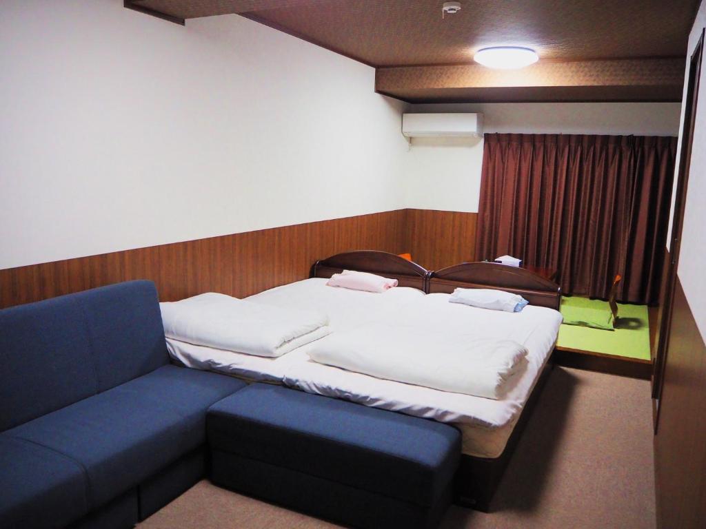 Cette chambre comprend un lit et un canapé bleu. dans l'établissement Syofuso, à Yumura