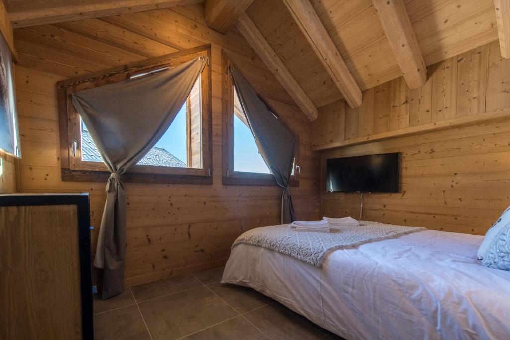 - une chambre dans une cabane en rondins avec un lit et une télévision dans l'établissement ODYSSEE B201 - Magnifique Duplex sur les pistes, à La Toussuire